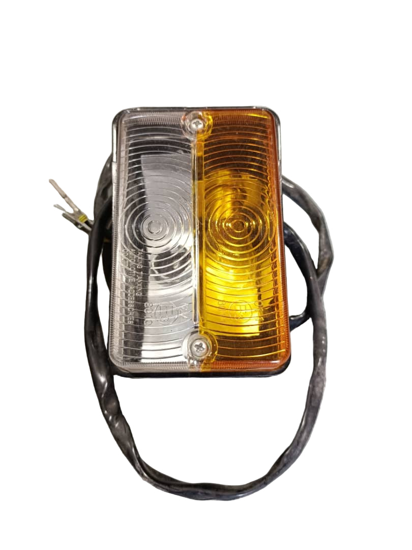 Amber and clear vehicle marker light on a gray surface